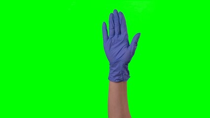 Woman hand in a medical blue glove showing gesture of welcoming. Doctor arm in protective glove gesturing hello gesture and waving palm. Close up on green screen background.