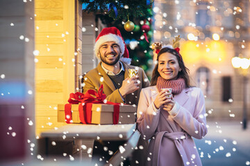 Young romantic couple holding gift box having fun outdoors in winter before Christmas.