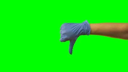 Foto op Plexiglas Woman hand in latex blue glove is showing thumbs down. Doctor arms in protective medical gloves gesturing sign negative, bad, unrecommended. Close up on green screen background. © kinomaster