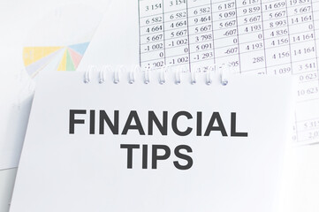 Fototapeta premium FINANCIAL TIPS . Text written on notepad with office tools and documents.