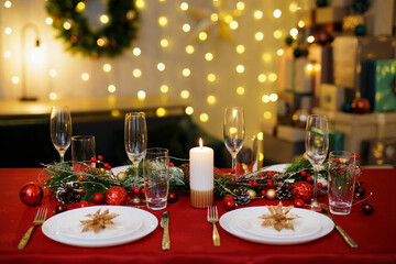 Table with plates and champagne glasses for christmas dinner. Garland on background