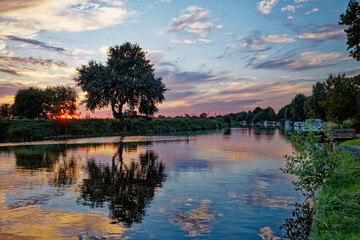 Sunset and cloud reflections in a river at dusk, East Frisia, Lower Saxony, Germany