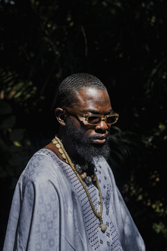 portrait of an african man in an agbada around palm trees