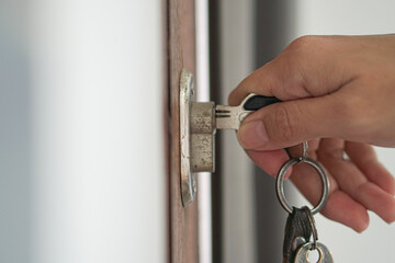 Woman using a key to open the lock of the front door