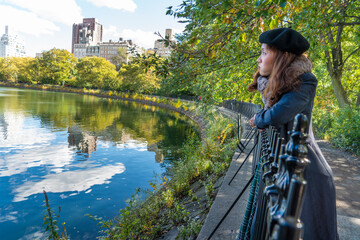 Asian women tourists go to see the city view reflecting water at the pond in Central Park