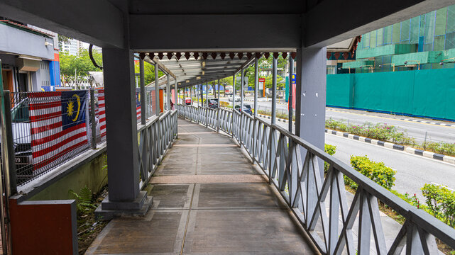 Kuala Lumpur, Malaysia - August 21, 2022: Covered walkway through the city center of KL. Covered footbridge protects pedestrians from heavy rain and also the hot sun. Malaysian Flag at the railing