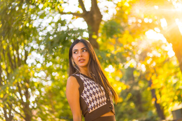 A caucasian brunette woman in autumn at sunset in a natural city park, autumn lifestyle