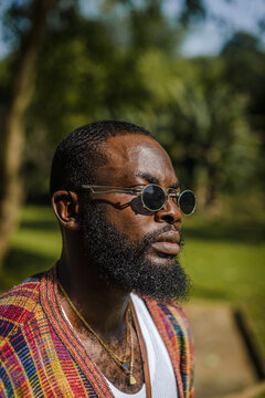 A closeup of a black man in sunglasses in a garden