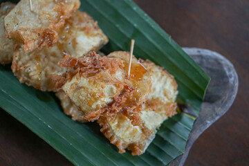 deep fried sliced tela on a banana leaf on wooden plate