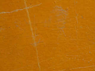 The texture of a wooden floor painted with orange paint. Close-up of the floor surface with scratches, scuffs and small debris