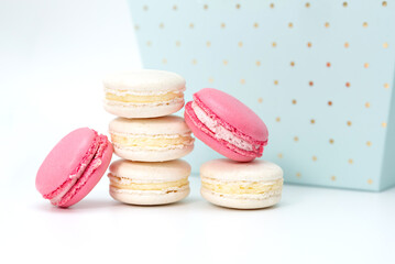 Several white and pink macaroon cakes on the background of a blue gift box