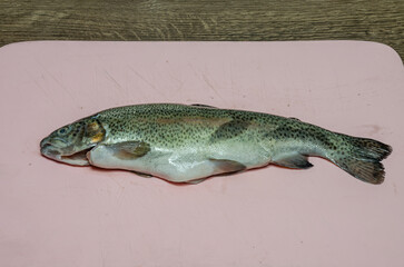The cook cuts rainbow trout on a cutting board