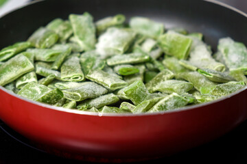 Frozen green beans in a pan ready for cooking. Vegetable preservation. Selective focus