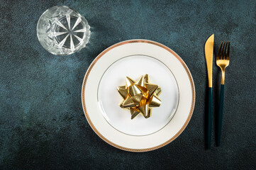 Christmas table setting with modern dishware and decorations on dark background. Top view. New Year place setting. Christmas tableware with decorations. Christmas place setting