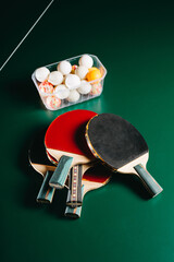 Ping pong rackets and box of balls on green gaming table