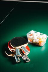 Ping pong rackets and box of balls on green gaming table
