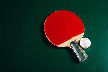 Ping pong racket and a ball are lying on a green game table