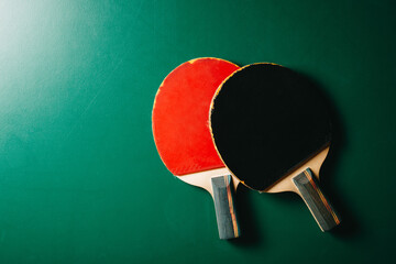 Two ping pong rackets are on the green game table