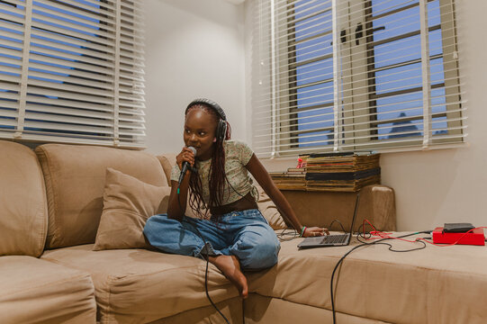 A woman recoding music with a microphone and laptop