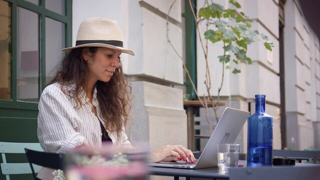 Young woman working on laptop in outdoor caffeteria.