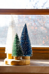 Colourful Christmas trees on the window. Trendy home decor for winter holidays.