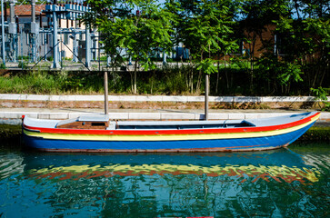 Fototapeta na wymiar Una barca di legno colorata si riflette in un canale di Murano a Venezia