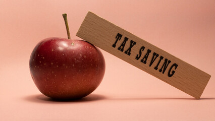 Tax saving inscription on wooden surface. Apple pink background concept.