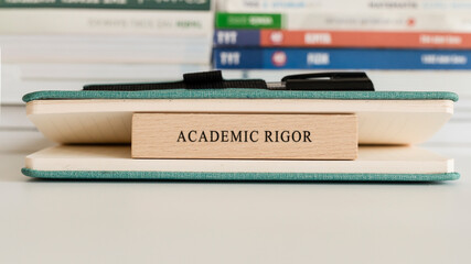 Academic Rigor writing on wooden surface. Book and wood concept. Education and work.