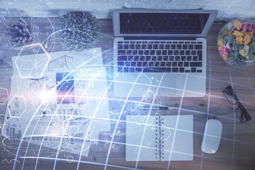 Double exposure of map hologram drawing over study table background with computer. Concept of international network. Top view.