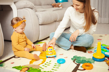 Mother and daughter play together, learn, home room, fun, love and care. A one year old girl.
