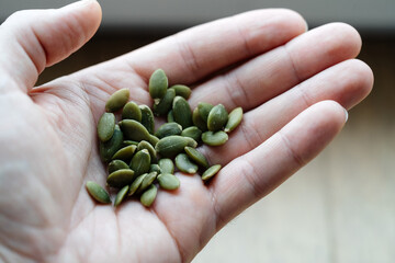 Pumpkin seeds peeled in a man's hand. Useful properties and vitamins in a handful of natural product.