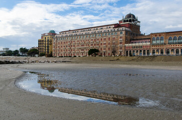 Il tetto di un grande albergo si riflette in un a pozza d'acqua sulla spiaggia del Lido di Venezia in una giornata invernale