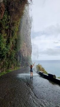 Cascata dos Anjos - woman standing under Angels waterfall in Madeira. vertical video for social media