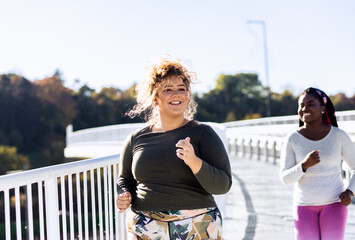 Two young plus size women jogging together.
