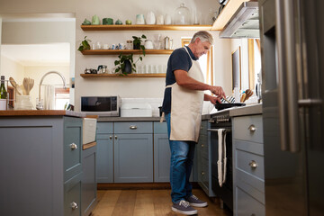 Senior man, cooking food and stove kitchen, lunch meal and dinner in frying pan in New Zealand home. Mature house chef with apron make easy recipe, cuisine and fresh diet for dining in retirement - Powered by Adobe