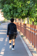 Back view of a young man walking outside. 