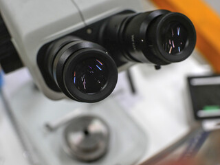 Fototapeta na wymiar Close-up on optics of a binocular microscope, its base is in blurred background.