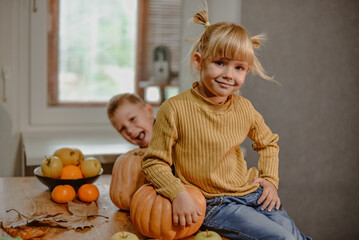 Boy and girl fool around decorating Halloween pumpkins.