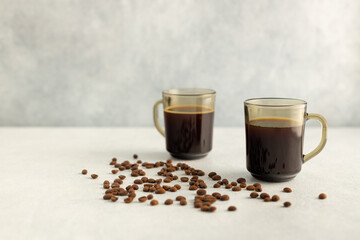 Coffee in a glass mug with coffee beans. Cold summer drink on a light gray background
