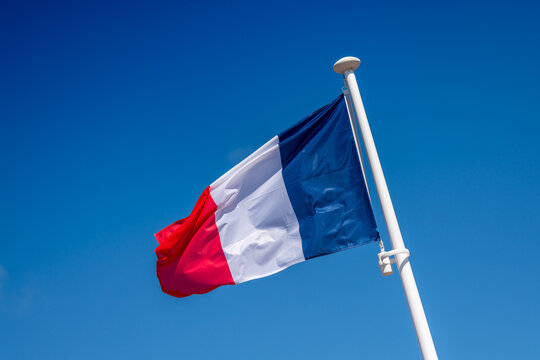 French flag unfurled in front of a blue sky