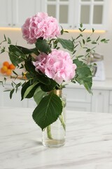 Beautiful pink hortensia flowers in vase on kitchen table