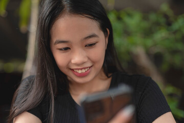 A candid shot of a beautiful Asian girl smiling at her cellphone.