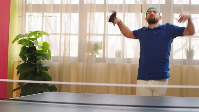 Good looking guy playing on the ping pong he get excited to win the game he hitting the ball with the paddles then start to dancing he wearing the uniform and are full equipment. Shot on ARRI Alexa
