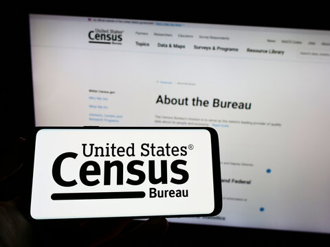 Stuttgart, Germany - 10-23-2022: Person Holding Cellphone With Logo Of US Agency United States Census Bureau (USCB) On Screen In Front Of Webpage. Focus On Phone Display.