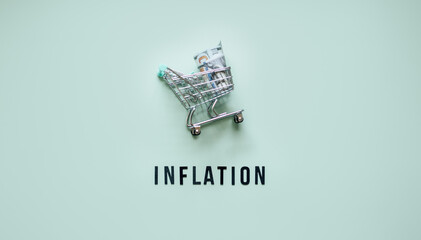 Shopping basket cart with dollars cash and word Inflation on blue background. Inflation financial...