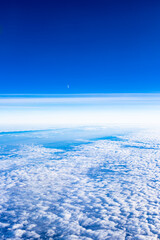 The sky from the plane window. Clouds below against the blue sky
