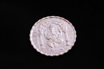 Close up of a silver coin engraved with image of Lord Ganesha.