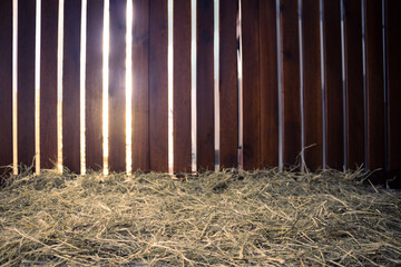 background of a barn with the sun's rays passing through the wooden fence and straw or hay floor