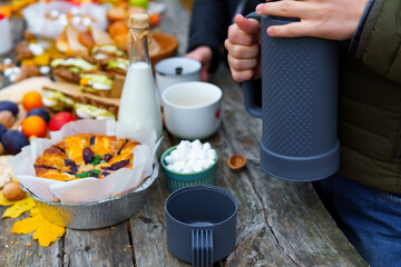 picnic in the autumn season, food on a wooden table, hot tea, pastries and sandwiches