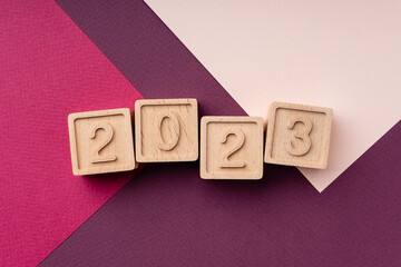 Wooden cubes with the numbers 2023, laid out on a bright red background, flat lay, top view,...